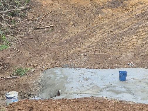 Creek crossing with a cut earth ramp leading down to a new concrete causeway over a culvert pipe