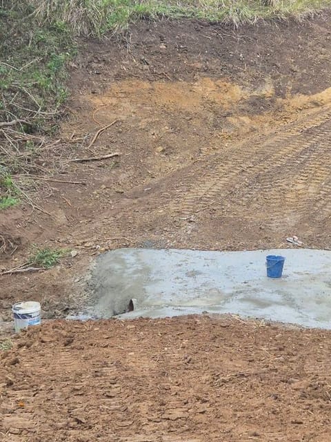 Creek crossing with a cut earth ramp leading down to a new concrete causeway over a culvert pipe